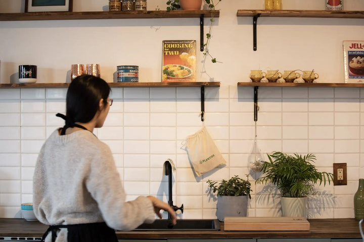 Woman walking in kitchen with eco friendly and plastic free essentials.