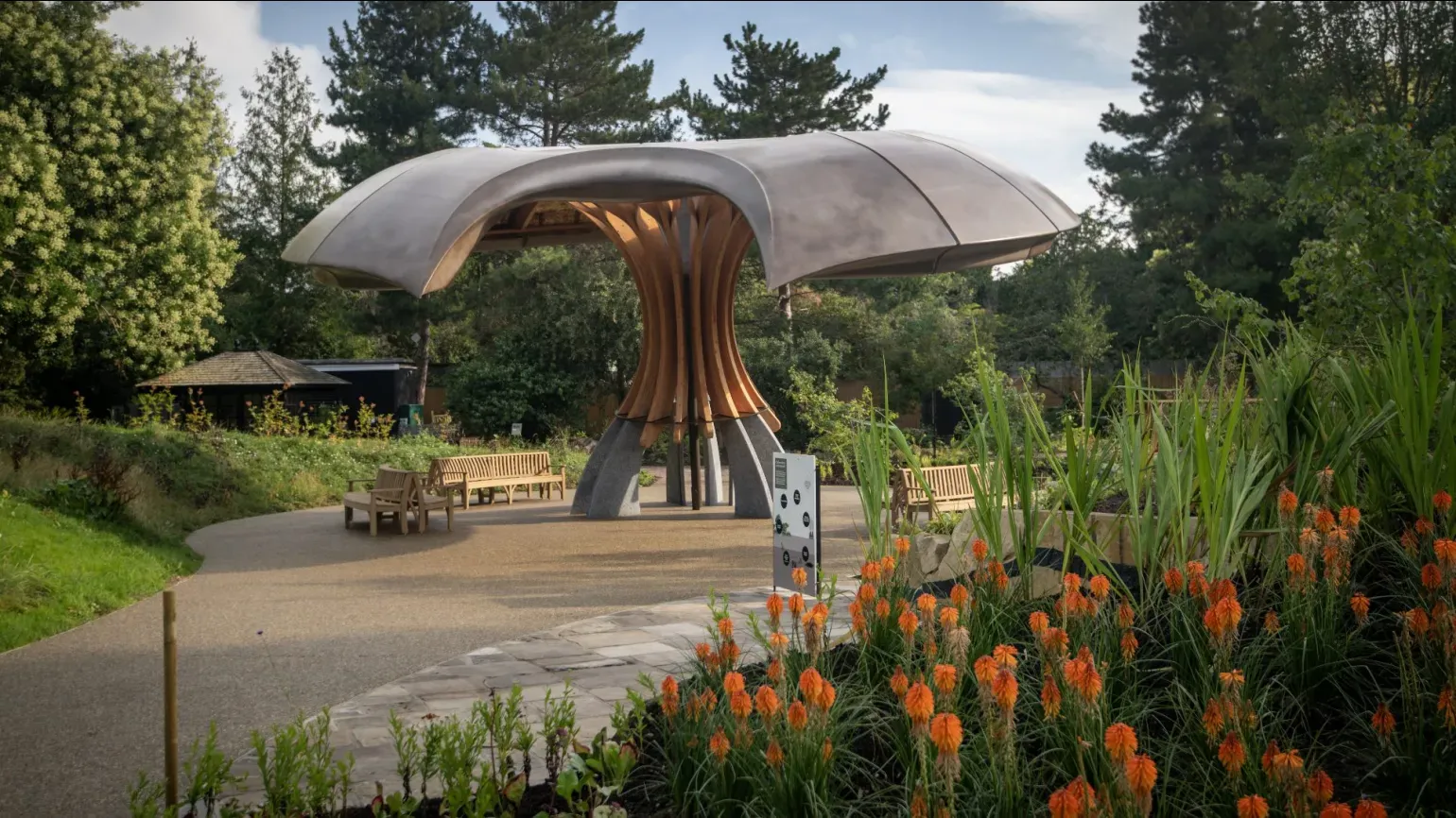 A large mushroom like structure in the Carbon Garden at Kew Gardens with two people looking up at it