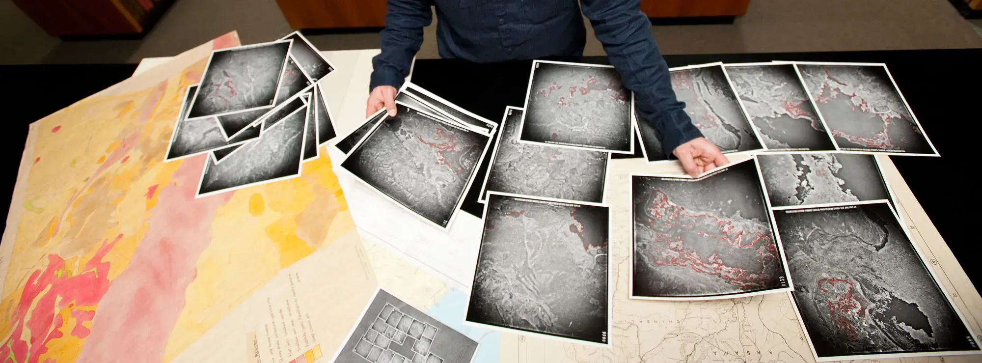 Researcher with table full of map print outs