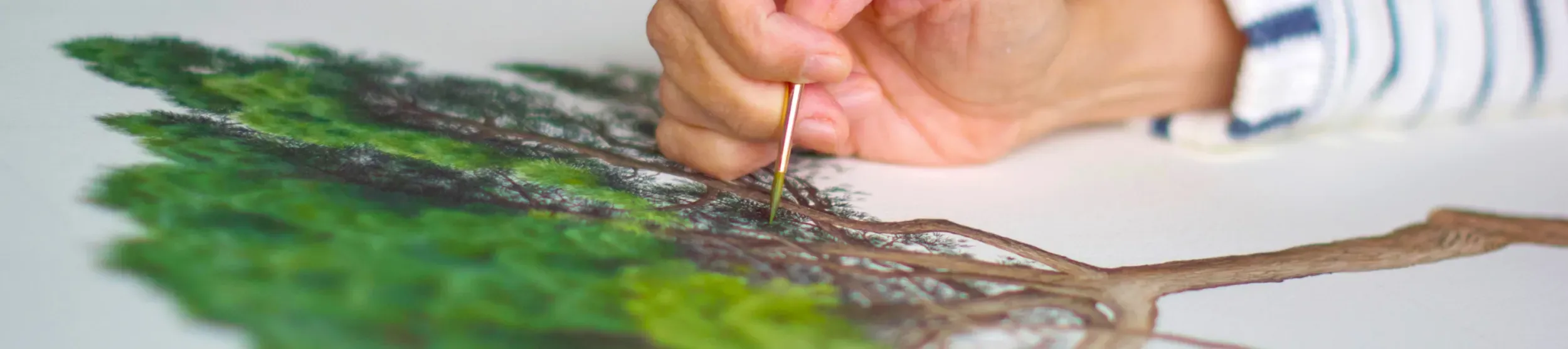 A hand painting a green tree