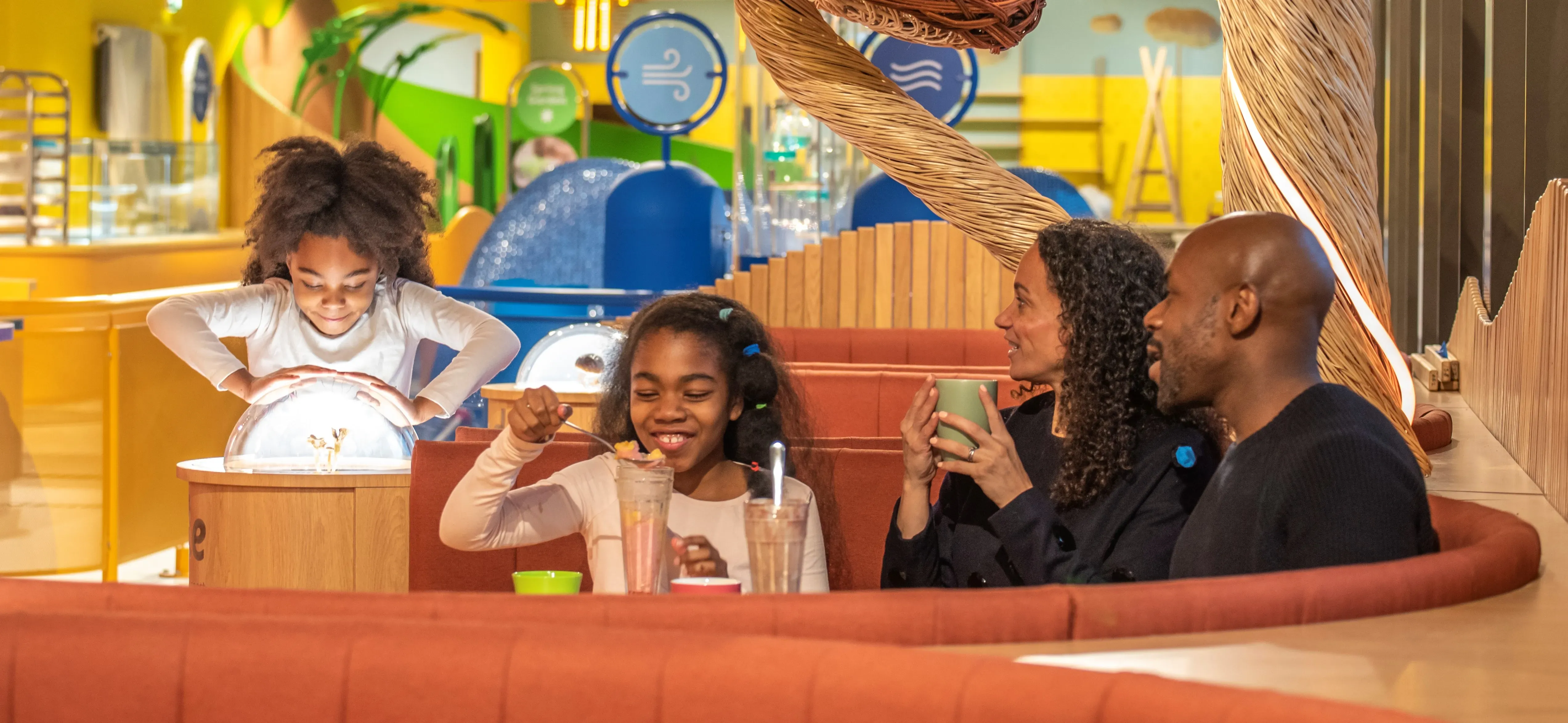 A family of four enjoys food in a colourful restaurant 