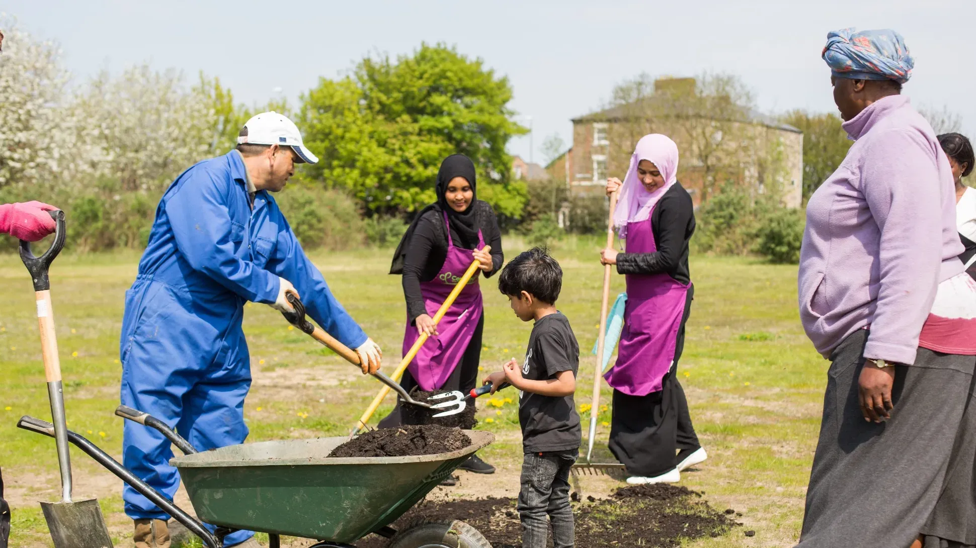 Women and children take part in an outreach project,putting soil into a wheelbarrow
