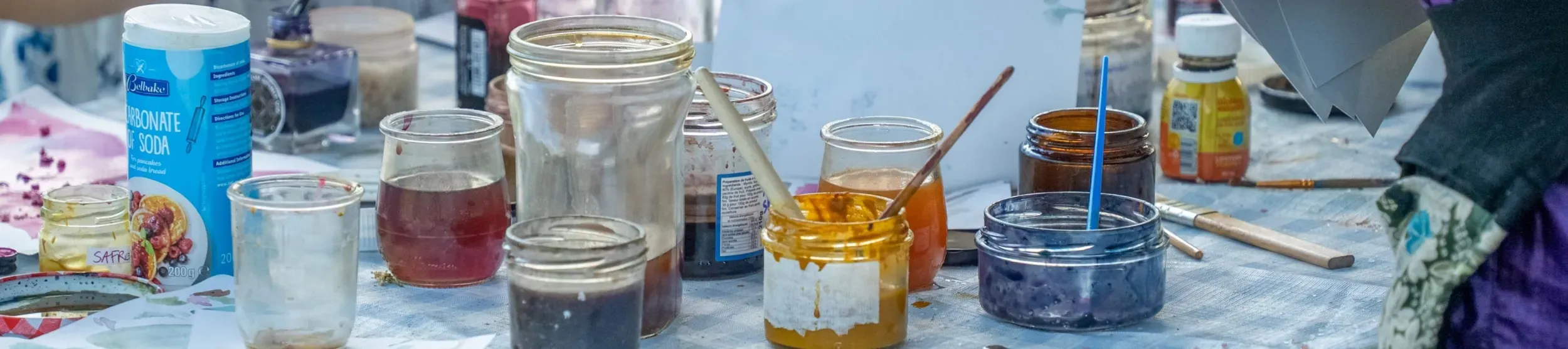 Paint pots and art supplies on a gingham table