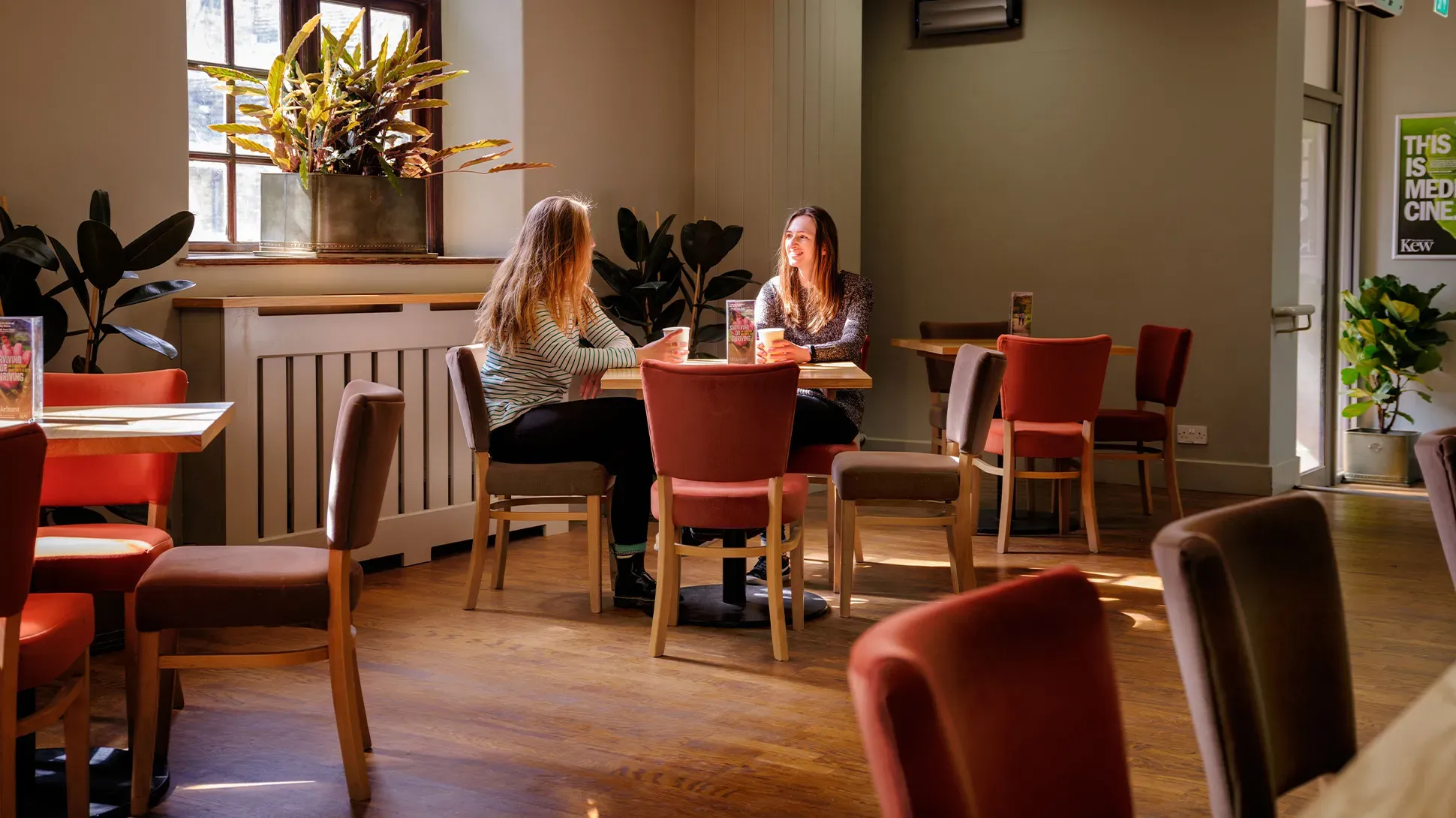 Two women sit at a table in Stables Pantry cafe. 
