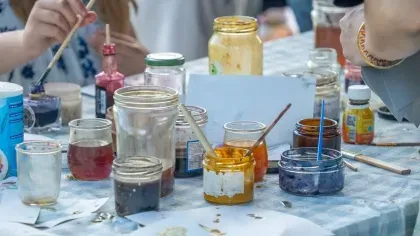 Paint pots and art supplies on a gingham table