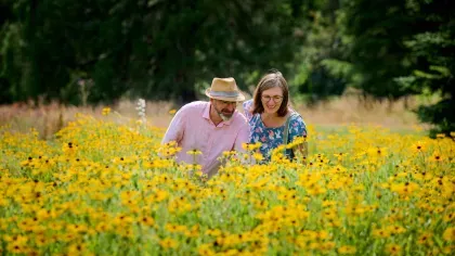 Two adults in a field of yellow rudbeckia flowers