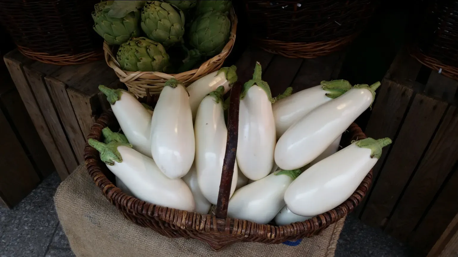 Several white aubergine fruit in a basket